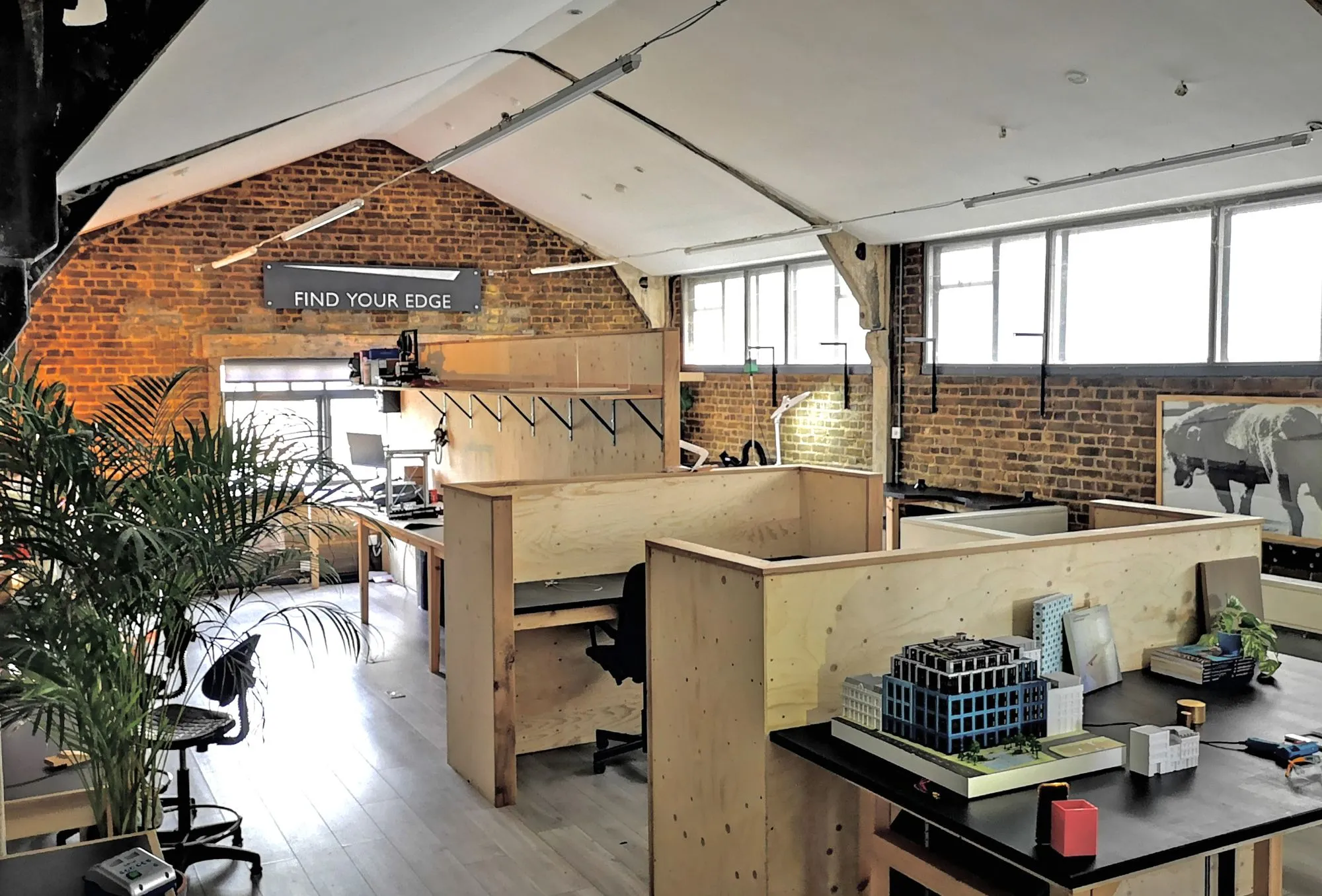 The makerspace floor at Hone Limehouse: plywood benches, brick walls and the pitched roof