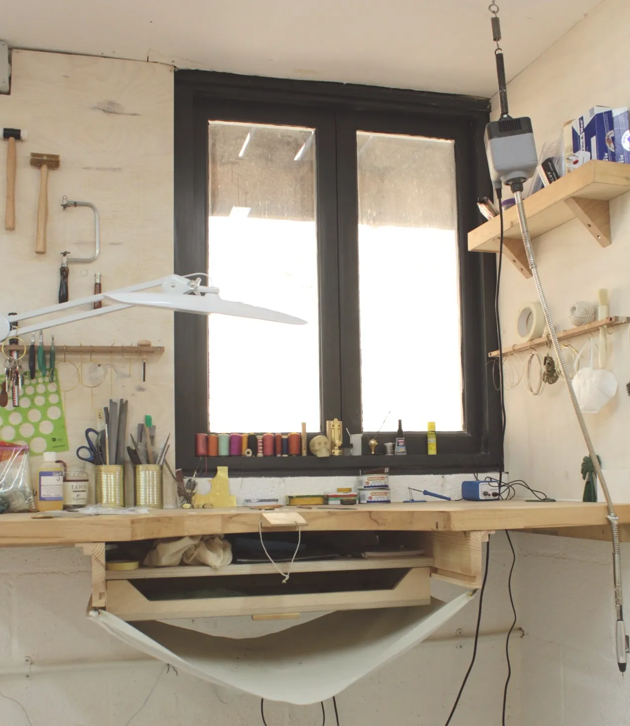 A bench by the window with tools on the wall