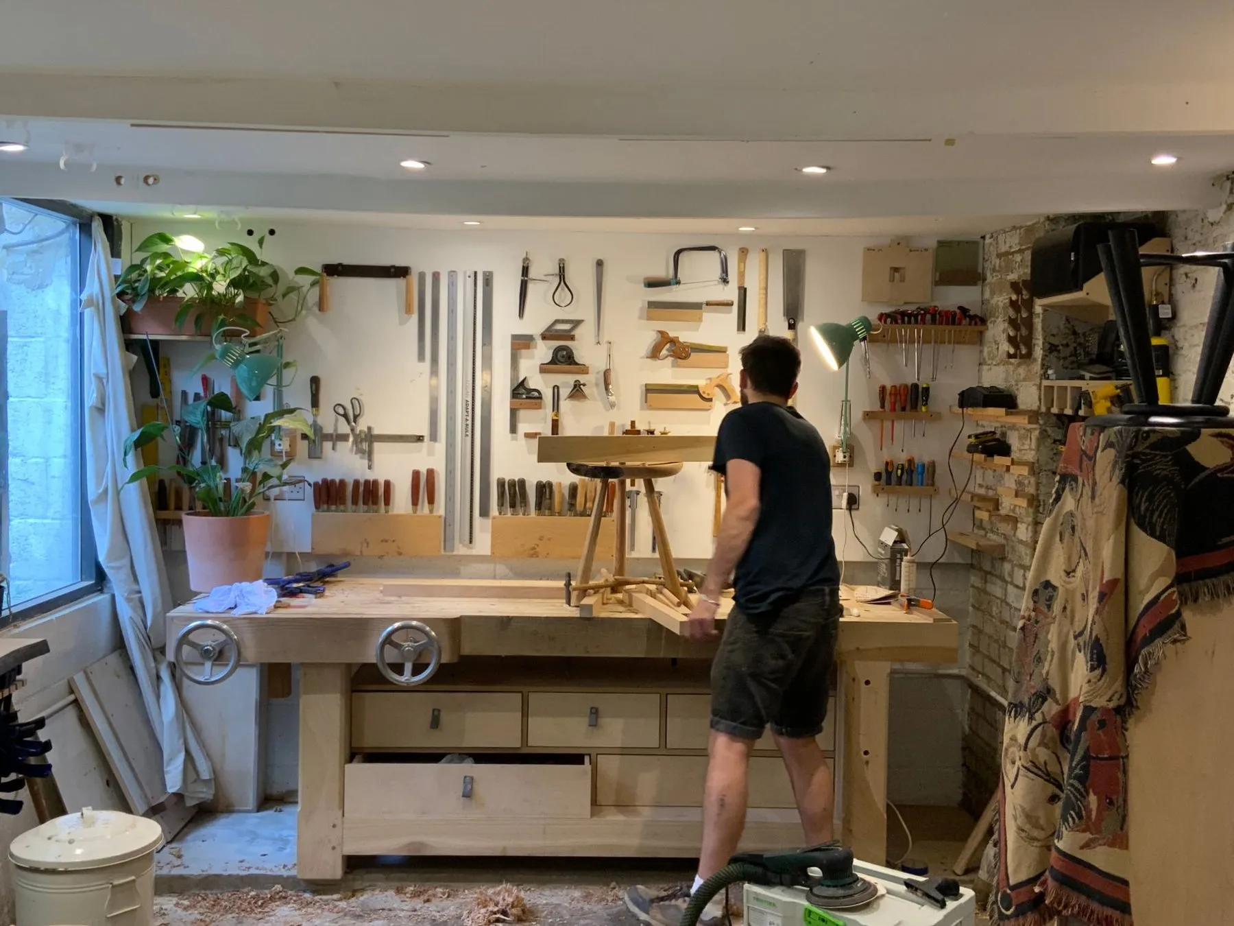 A maker at the workbench in front of the tool wall